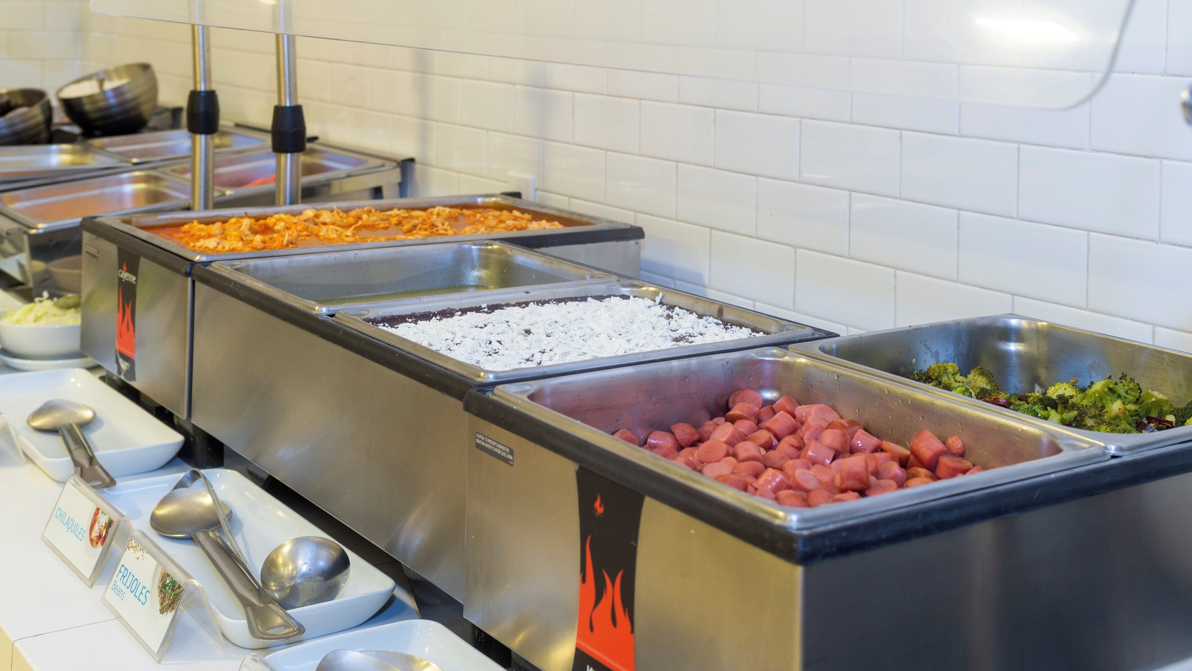 Un bufé con diversas opciones de comida, incluyendo frijoles, chili y salchichas.