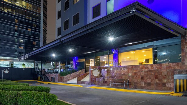 A hotel entrance with a covered outdoor area, a staircase, and a bench. - Holiday Inn Express Mexico Santa Fe by IHG (Mexico City)