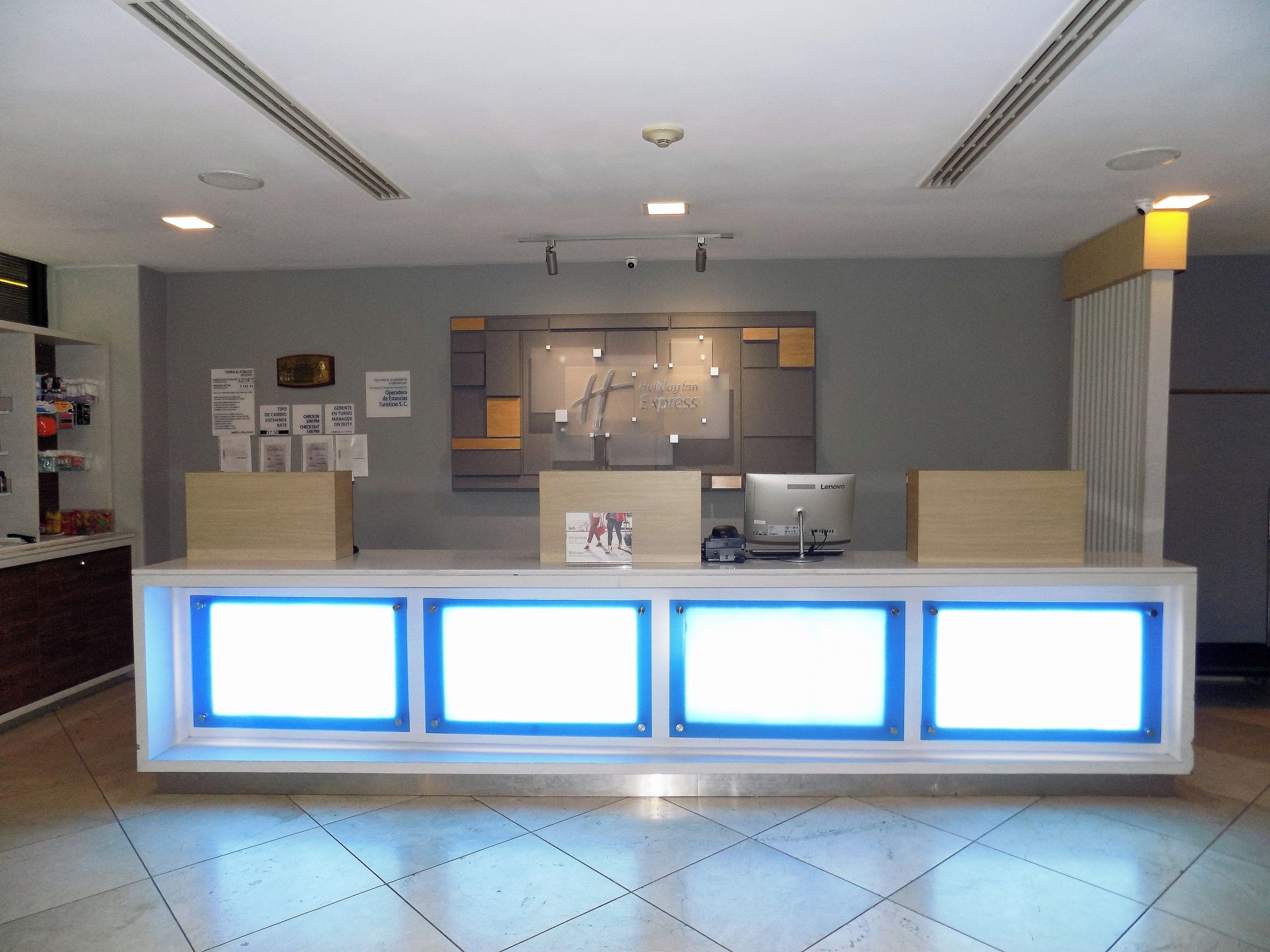 Un mostrador de recepción de diseño moderno, con un monitor de pantalla plana, una caja registradora y un pequeño expositor.