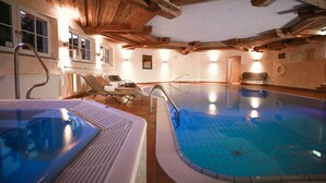A large indoor swimming pool with a wooden ceiling and tiled floor. - Seehotel Wassermann (Seeon-Seebruck)