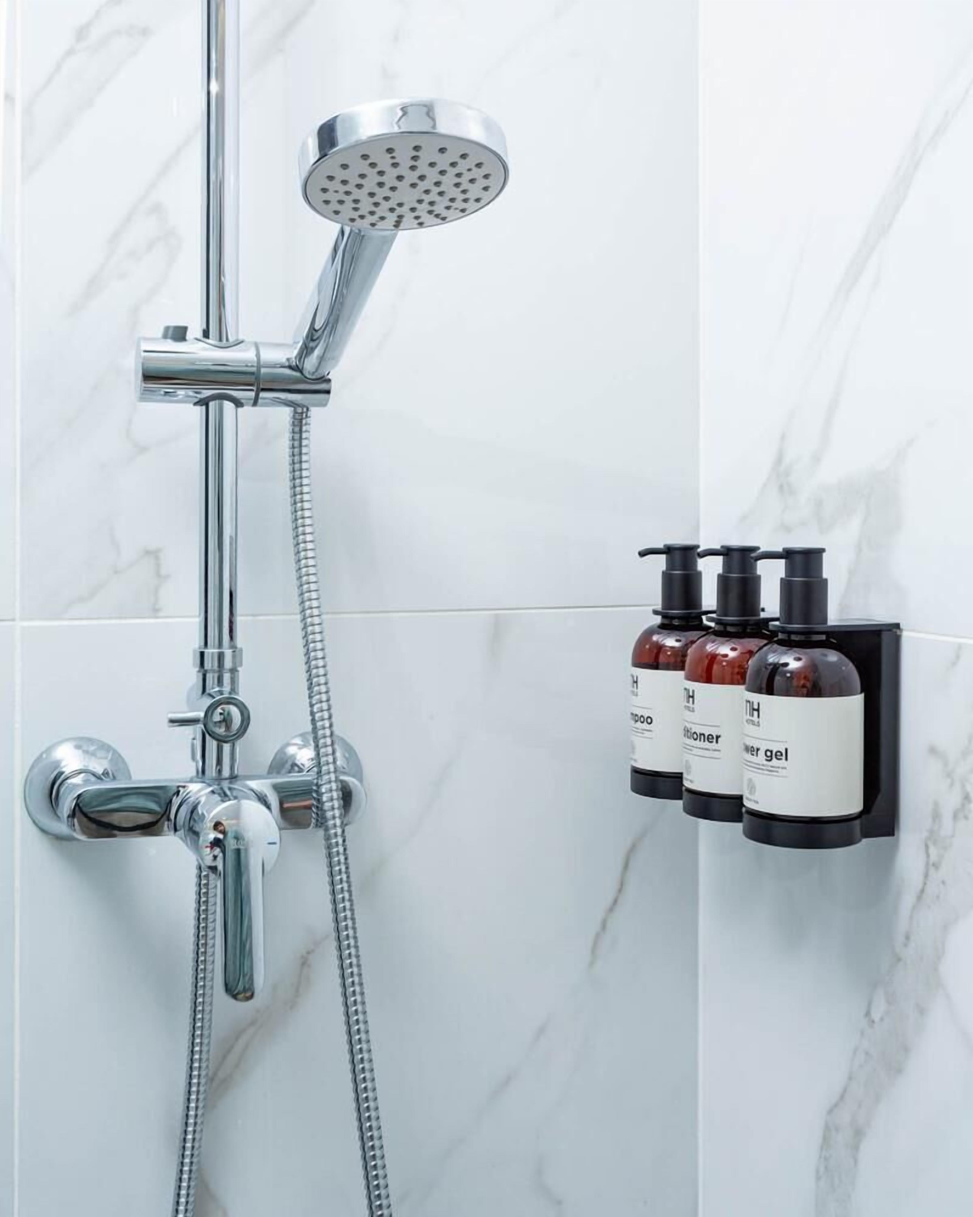 A modern bathroom with a shower, a handheld showerhead, and a wall-mounted soap dispenser.