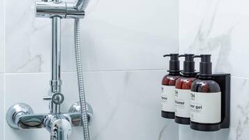 A modern bathroom with a shower, a handheld showerhead, and a wall-mounted soap dispenser.