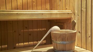 Un banco de sauna de madera con un cubo que contiene una cuchara de madera.