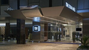 A modern hotel entrance with a glass facade, a visible reception desk, and a sign reading "NH HOTEL." - NH Coimbra Dona Inês (Coimbra)