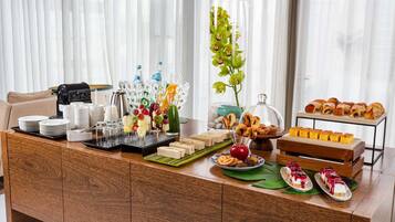 Una barra de desayuno con diferentes opciones de comida, como sándwiches, pastelería y brochetas de fruta.
