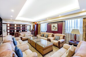 A spacious living room with a sofa set, a glass coffee table, and a decorative cabinet. - Grand Skylight Hotel Beijing (Beijing)