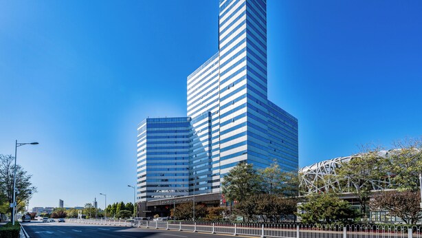 A modern high-rise hotel with a prominent corner entrance and a clear blue sky. - Grand Skylight Catic Hotel Beijing (Beijing)