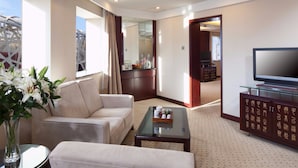 A modern hotel room with a sofa, a glass coffee table, a TV on a cabinet, and a large window with curtains. - Grand Skylight Catic Hotel Beijing (Beijing)