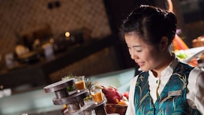 A person serving drinks at a bar with a layered drink dispenser. - Grand Skylight Catic Hotel Beijing (Beijing)