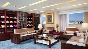 A spacious living room with a sofa, armchairs, a coffee table, and a bookshelf filled with books. - Grand Skylight Catic Hotel Beijing (Beijing)