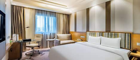 Ein Hotelzimmer mit einem großen Bett, einem Schreibtisch mit Lampe, einem Sessel und einem kleinen Tisch.