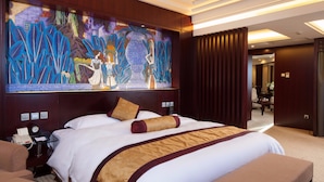A hotel room with a large bed, a desk with a phone, and a painting on the wall. - Grand Skylight Catic Hotel Beijing (Beijing)
