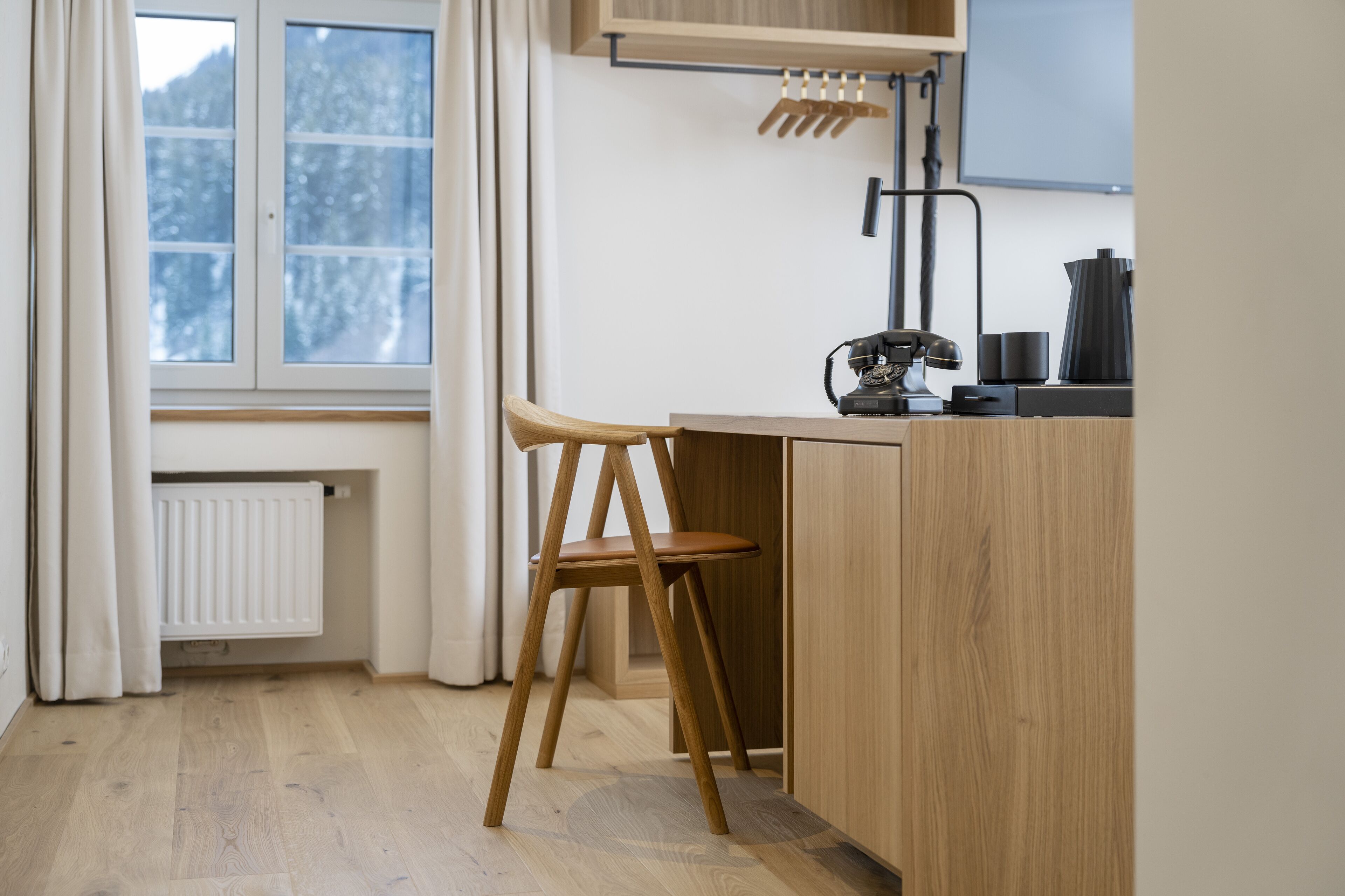 Eine Küche mit Holztisch und Stuhl, einem Heizkörper und einem Fenster mit Vorhängen.