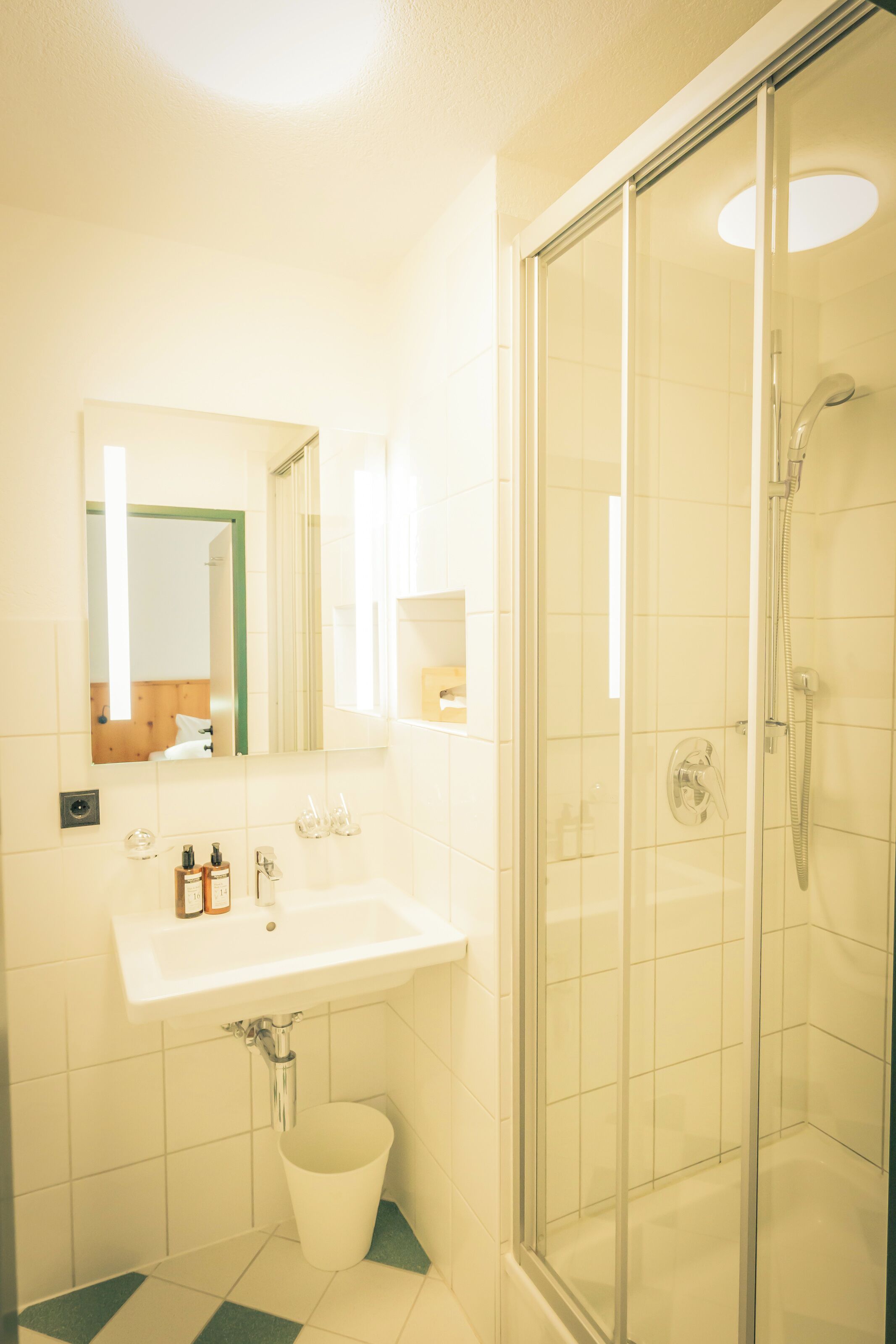 Un baño con lavamanos, espejo y cabina de ducha de vidrio.