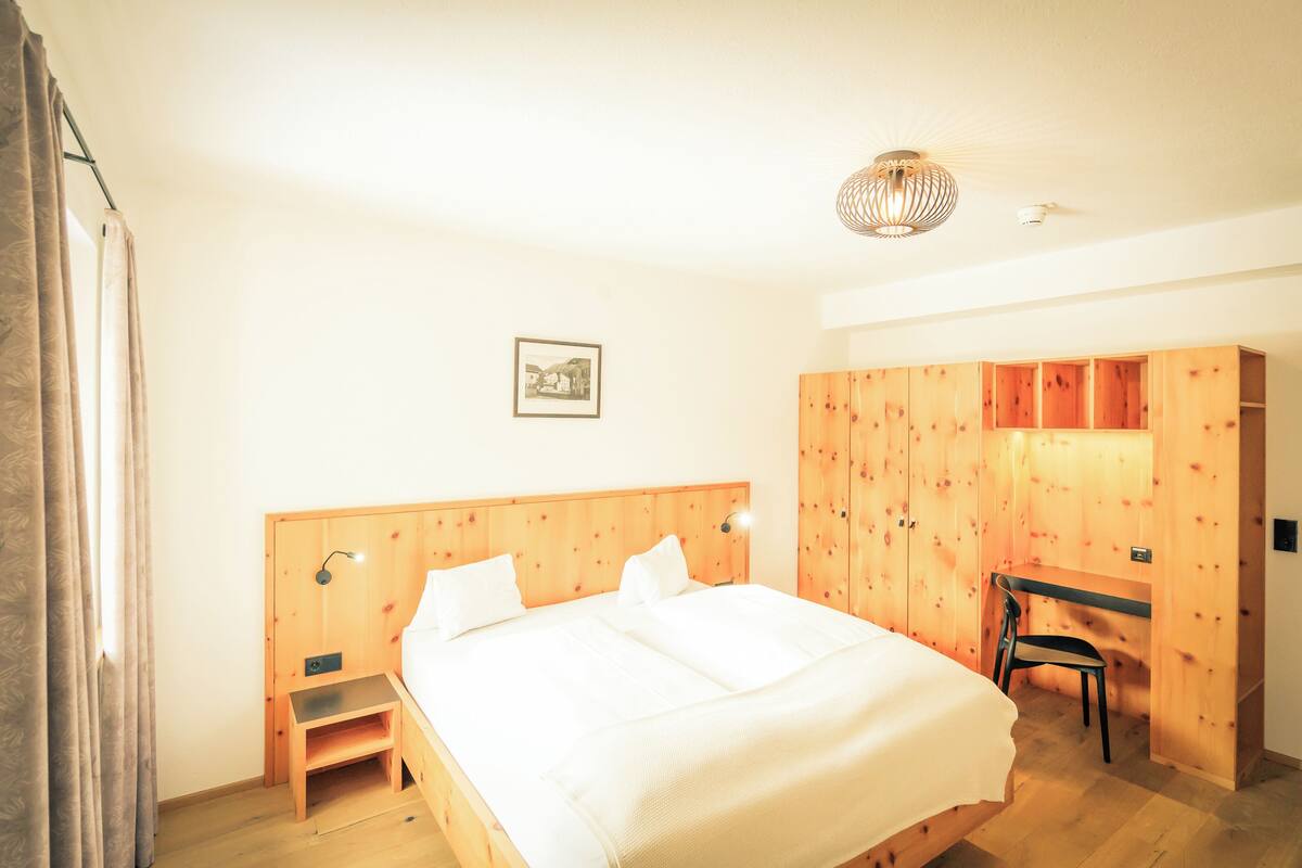 A bedroom with a wooden bed, a desk, and a wardrobe.