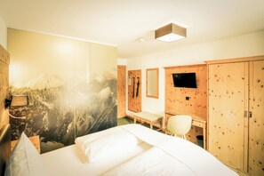 Une chambre d’hôtel équipée d’un lit, d’un bureau, d’une chaise, d’une télévision et d’armoires en bois.