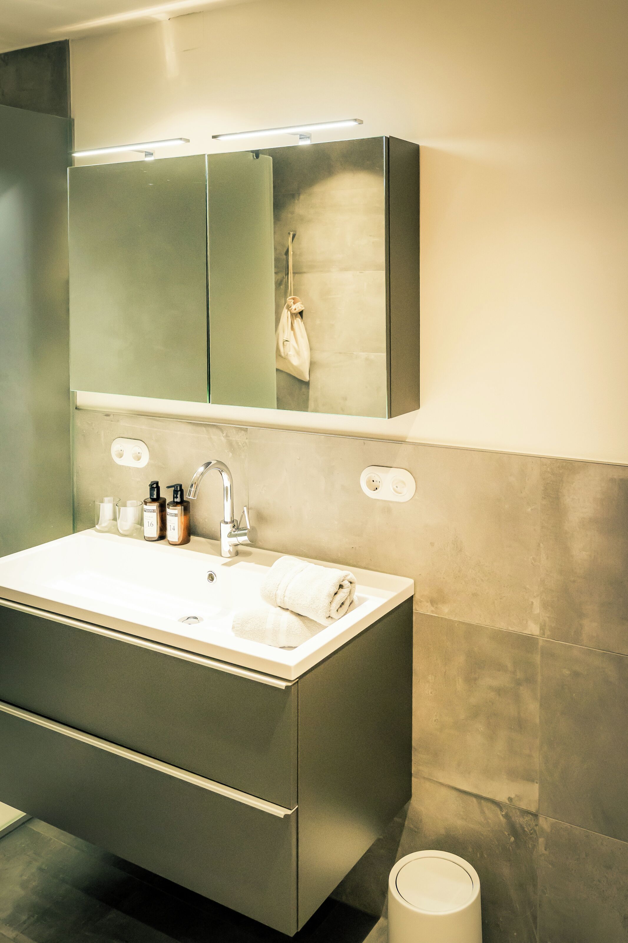 A modern bathroom with a large sink, mirror, and storage cabinets.