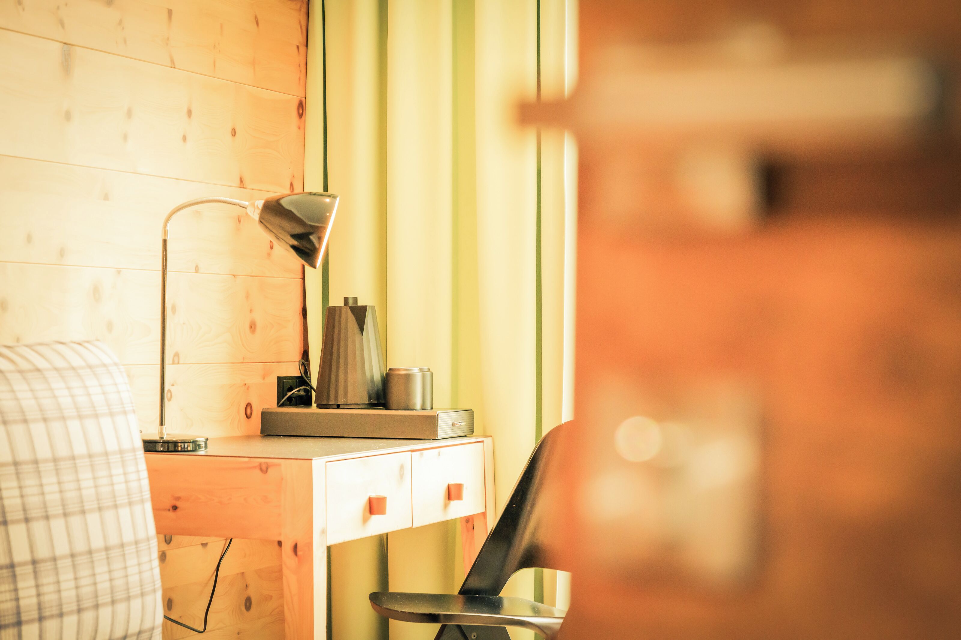 Un escritorio de madera con una lámpara, una taza y un pequeño dispositivo electrónico.
