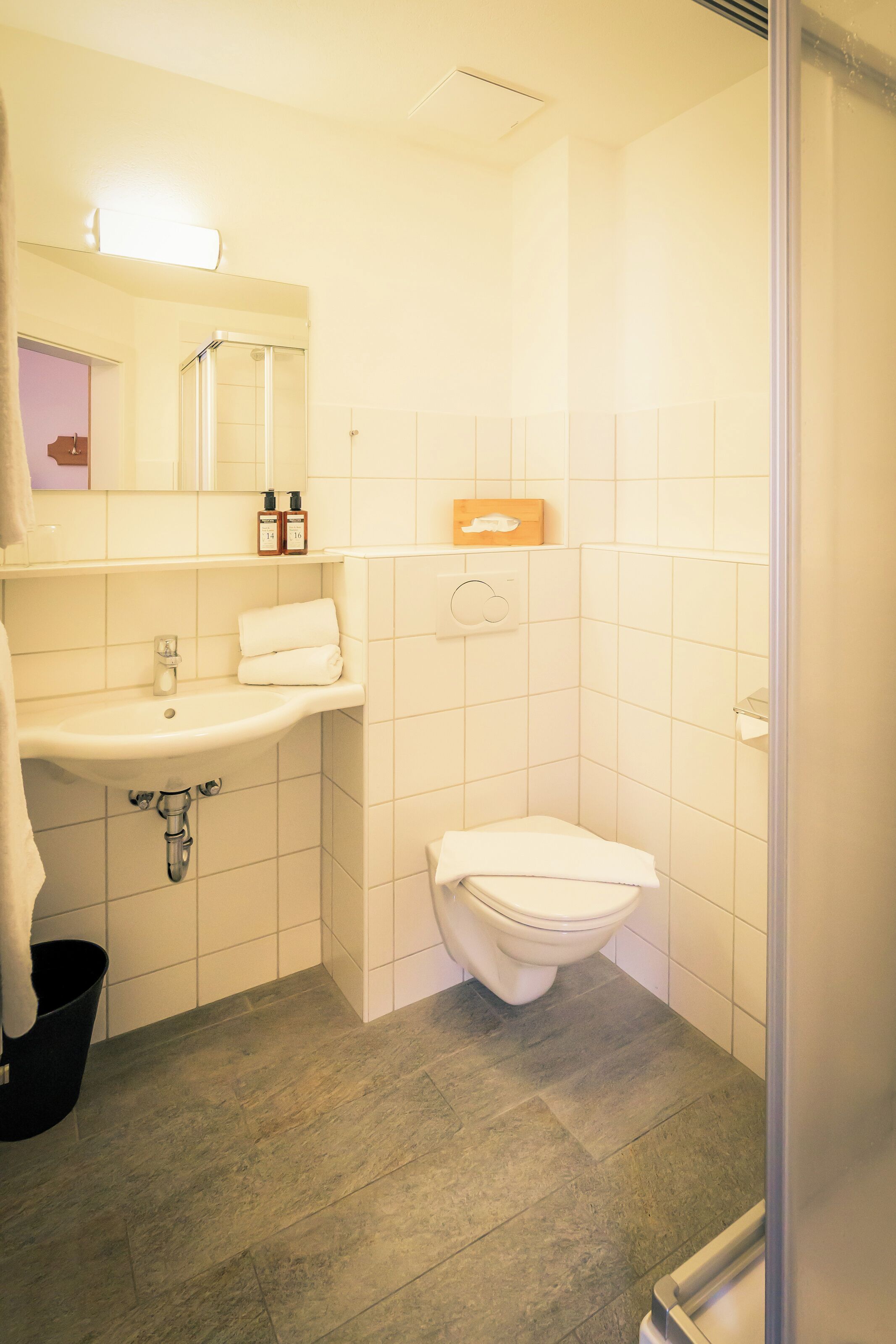 A bathroom with a sink, mirror, toilet, and shower.