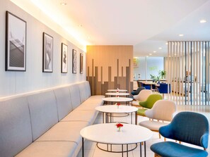 A modern lounge area with a long bench, round tables, and colorful chairs. - ibis Bangkok Sathorn (Bangkok)