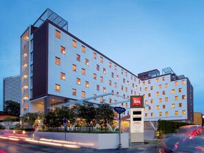 Un hôtel à plusieurs étages au design moderne, reconnaissable à son grand panneau « Ibis Hotels ».