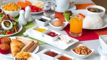 Une table dressée avec une variété d’aliments pour le petit-déjeuner, notamment des œufs, des toasts, des muffins et des boissons.