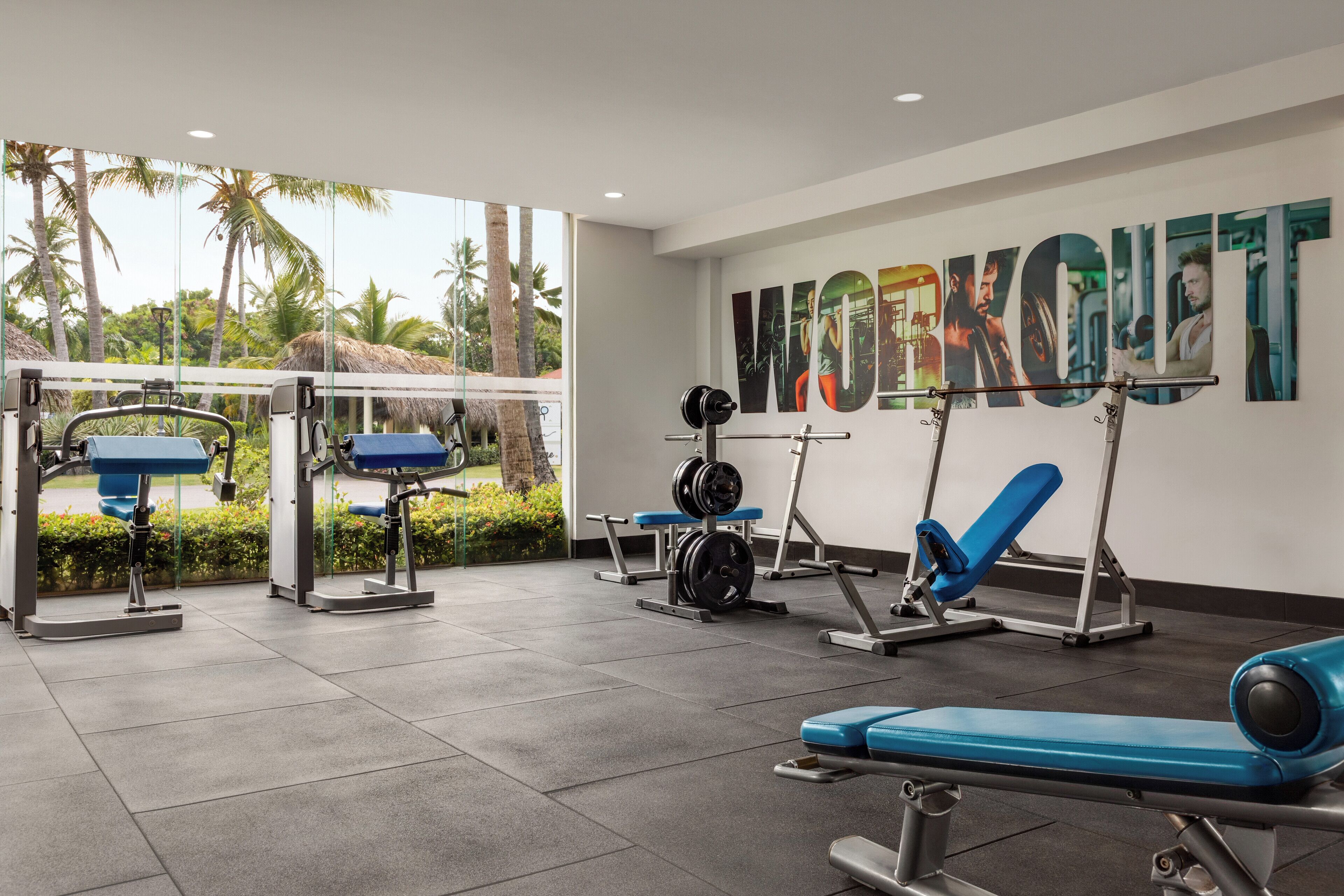 Un gimnasio con equipo de levantamiento de pesas y un gran cartel que dice 'WORKOUT'.