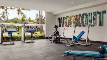 Un gimnasio con equipo de levantamiento de pesas y un gran cartel que dice 'WORKOUT'.