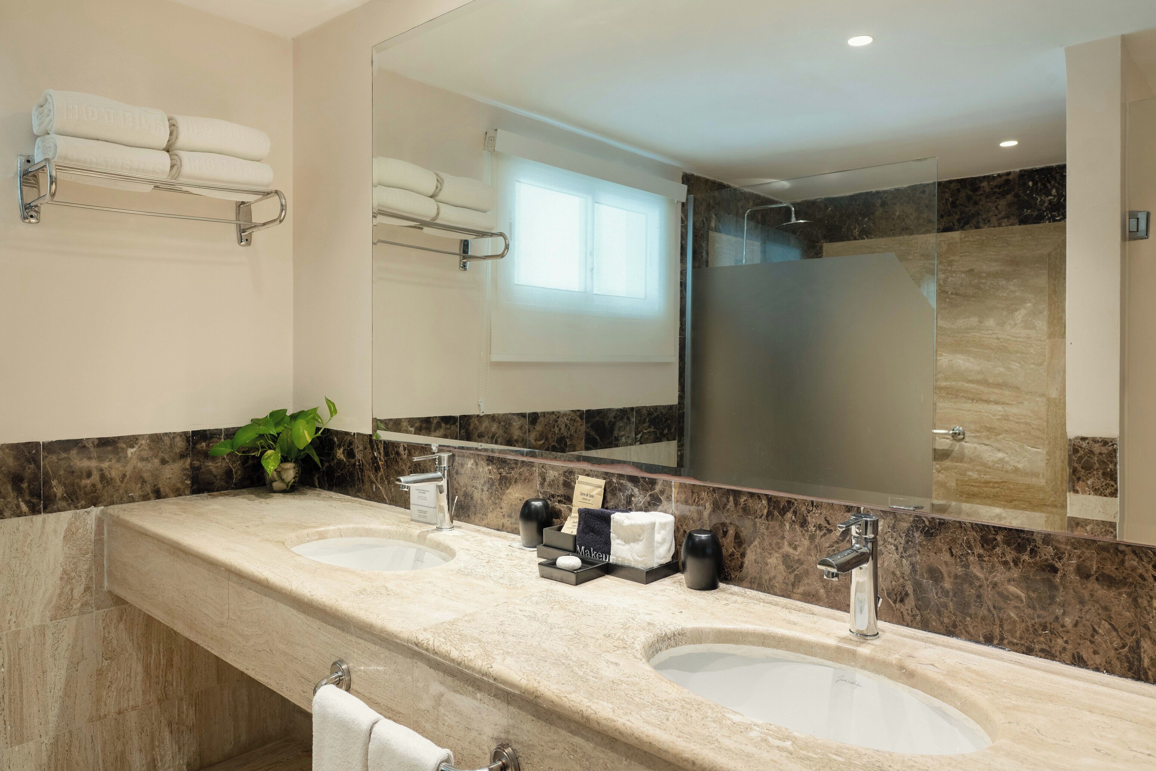 Une salle de bain moderne avec deux lavabos, un grand miroir et un espace douche.