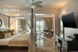 Habitación de hotel con cama con dosel, televisor, escritorio y vista al exterior.