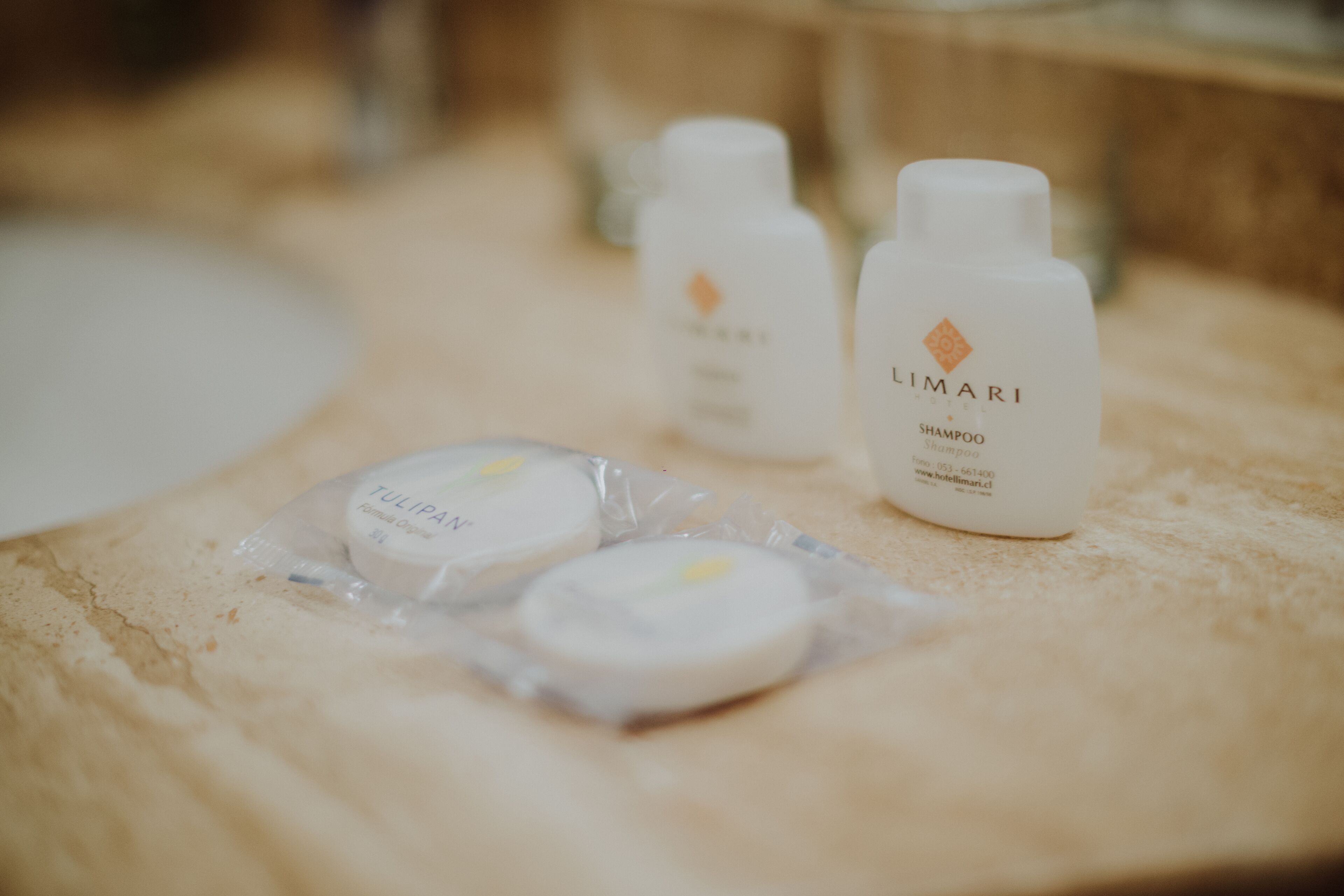 Una encimera de baño con artículos de aseo, incluyendo una botella de champú Limiari, una botella de acondicionador Limiari y dos productos envasados.