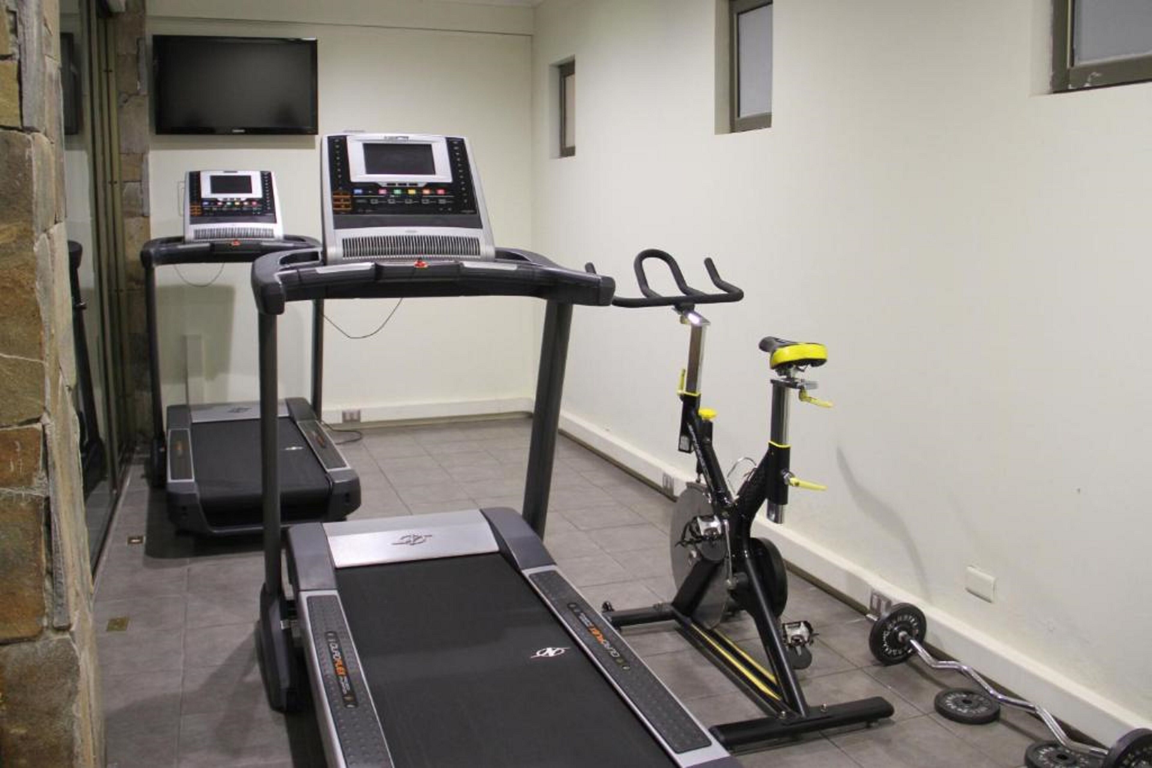 A fitness room with treadmills, a stationary bike, and weightlifting equipment.