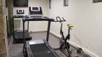 A fitness room with treadmills, a stationary bike, and weightlifting equipment.