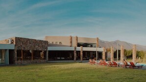 A modern building with a stone facade, large windows, and a pool area with lounge chairs.