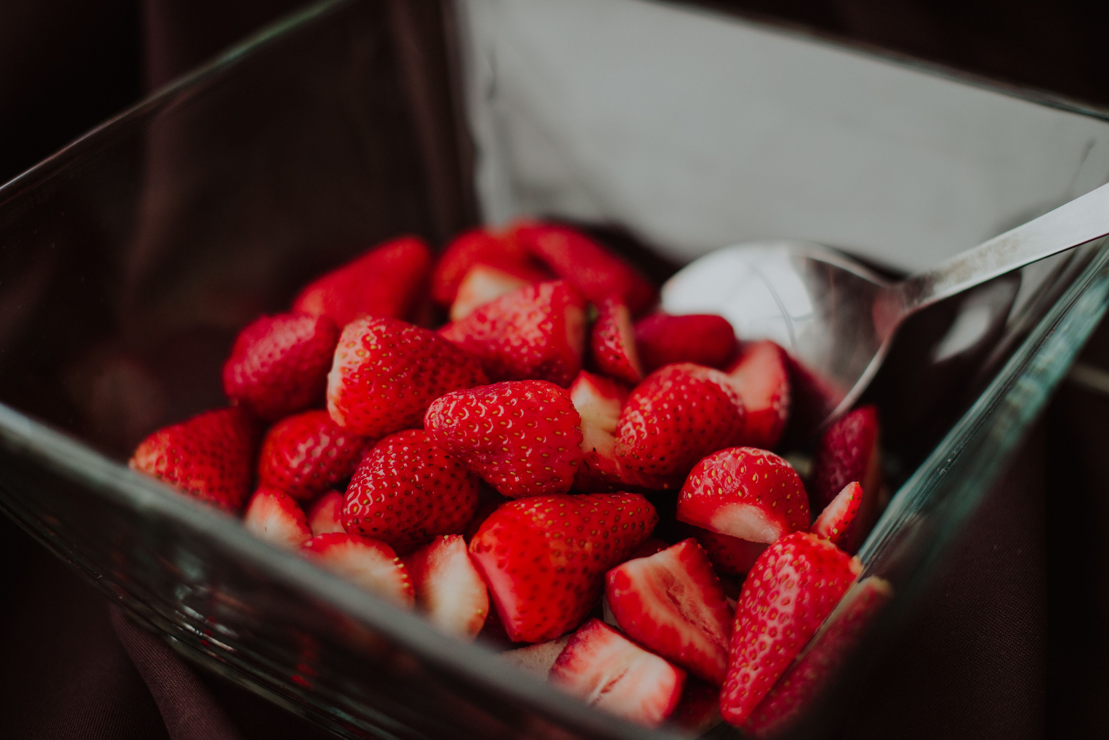 Un cuenco de vidrio lleno de fresas en rodajas.