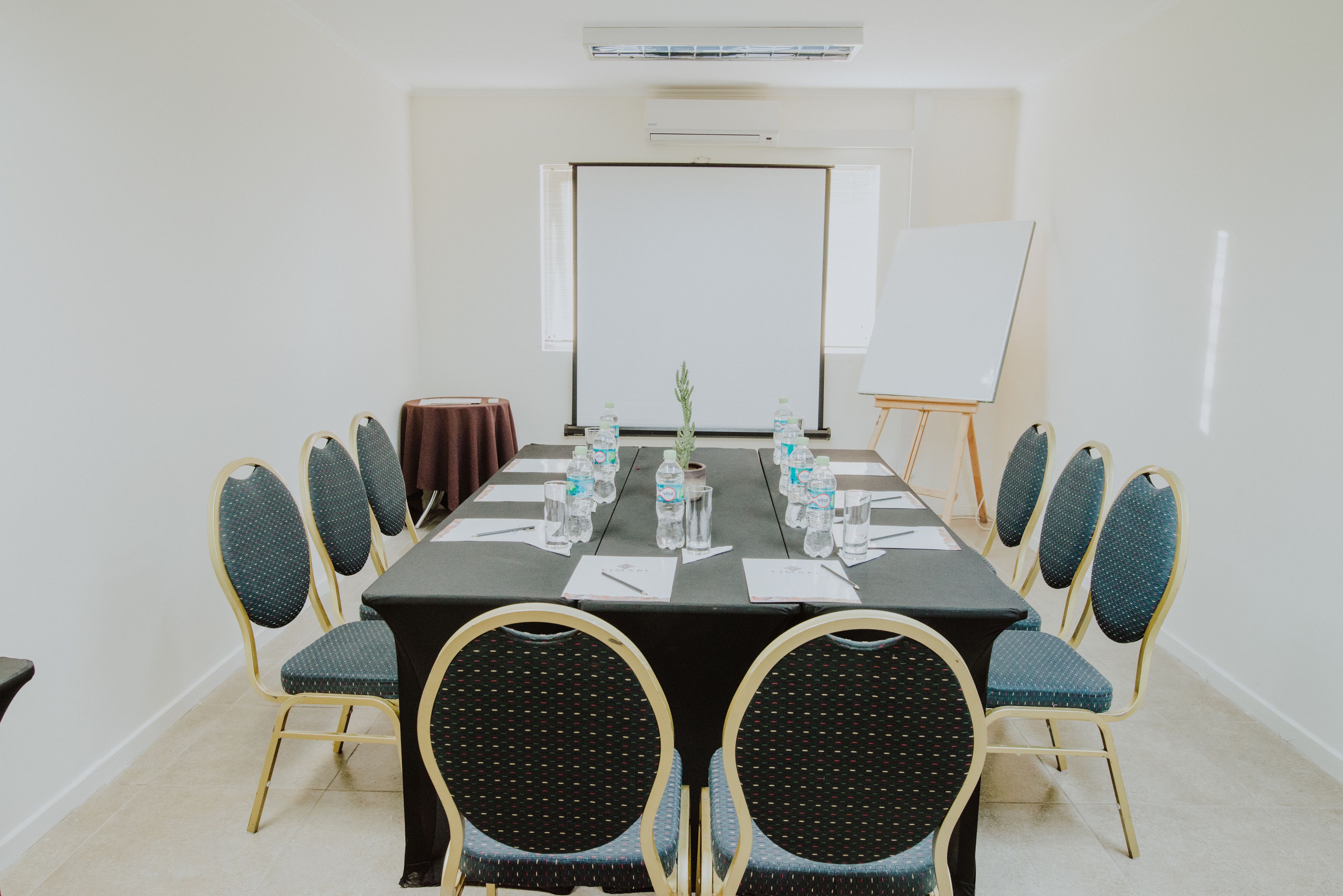 A conference room with a long table, chairs, a projector screen, and a whiteboard.
