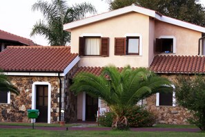 A two-story house with a stone facade, a tiled roof, and a small front porch. - Zeta Club San Teodoro Le Rose (San Teodoro)