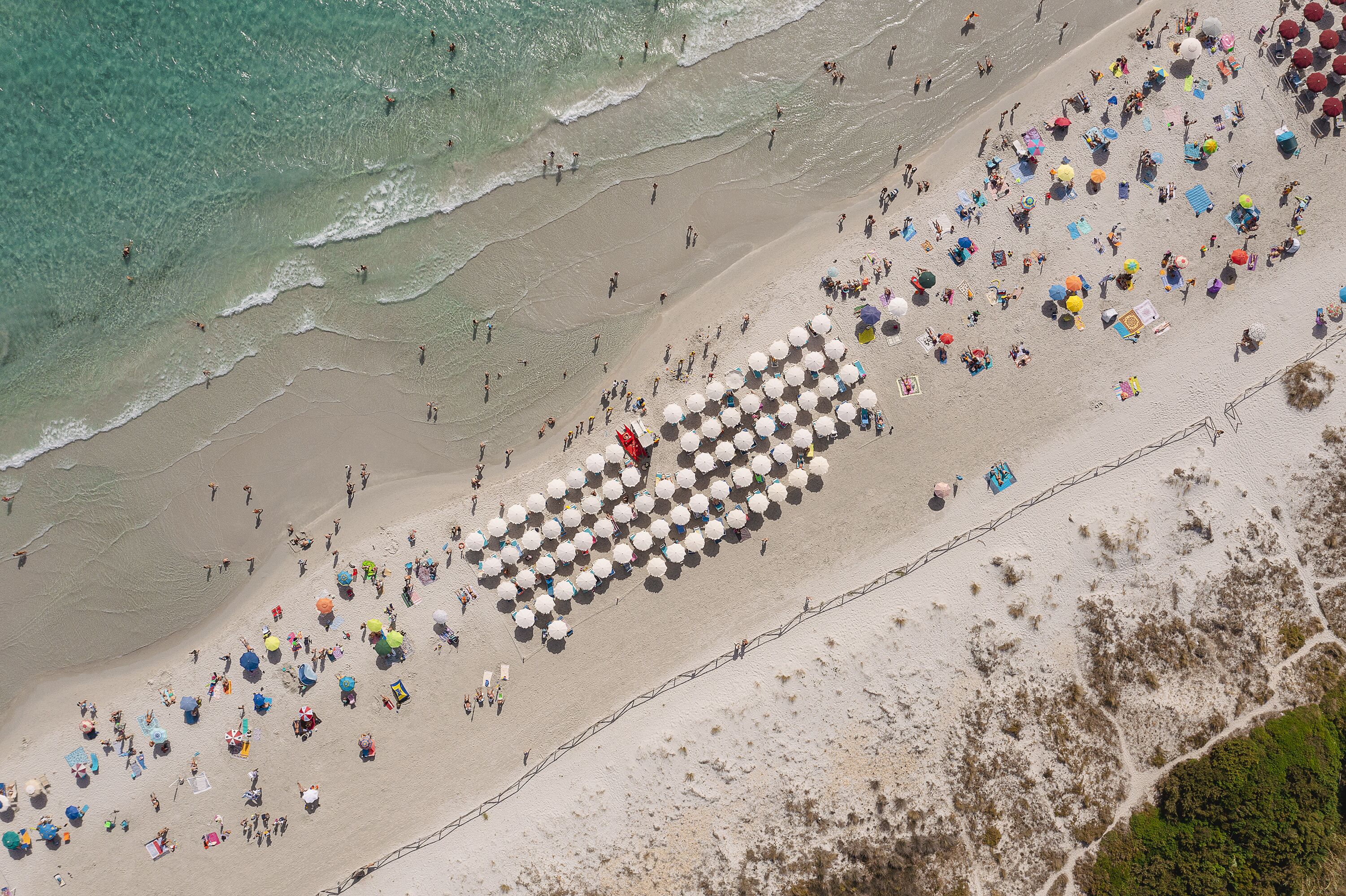 An aerial view of a beach with people and umbrellas.