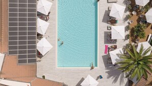 Eine Luftaufnahme eines Dachpools mit umliegenden Liegebereichen, Solaranlagen und klarem, blauem Wasser.