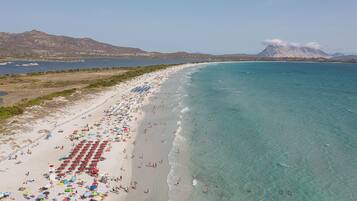 Una spiaggia con acque cristalline turchesi, una riva sabbiosa e montagne sullo sfondo.
