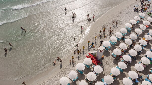 Ein Strand mit Reihen von Sonnenschirmen und Liegestühlen.