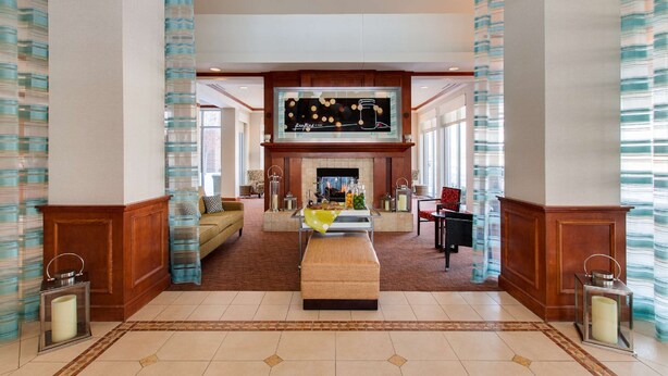 A spacious lobby with a fireplace, comfortable seating, and a large wall-mounted TV. - Hilton Garden Inn Naperville/Warrenville (Warrenville)