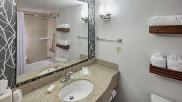Un baño moderno con lavamanos de granito, un espejo grande, un perchero y una zona de ducha.