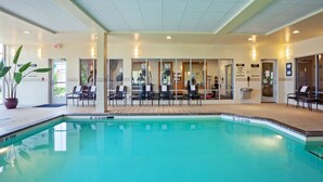 A pool area with a tiled deck, lounge chairs, and a potted plant. - Hilton Garden Inn Naperville/Warrenville (Warrenville)