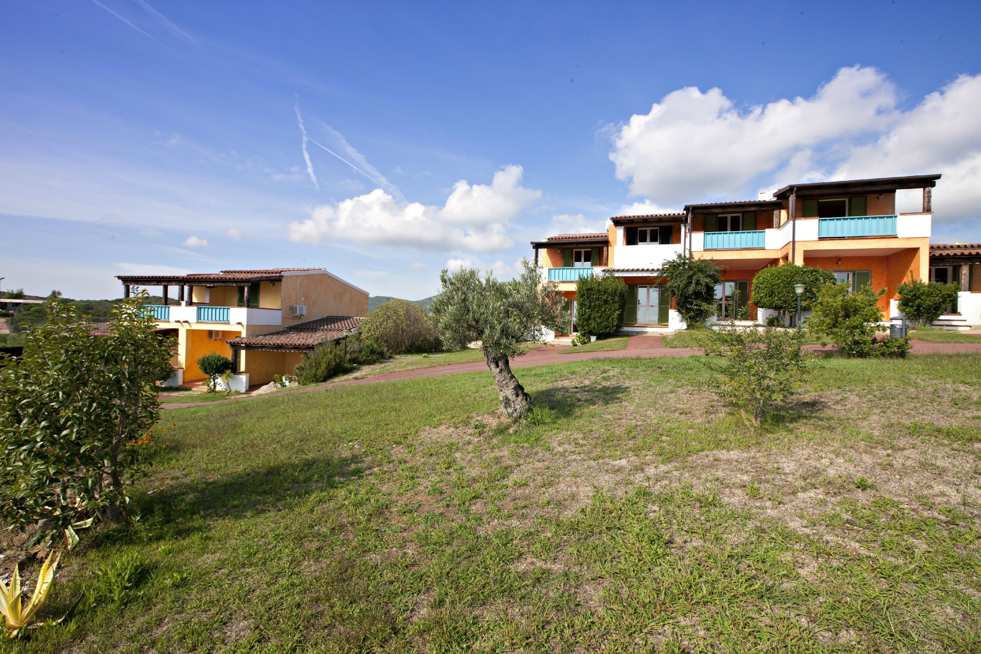 Un barrio residencial con varias casas de dos pisos, cada una con balcón y un pequeño jardín.