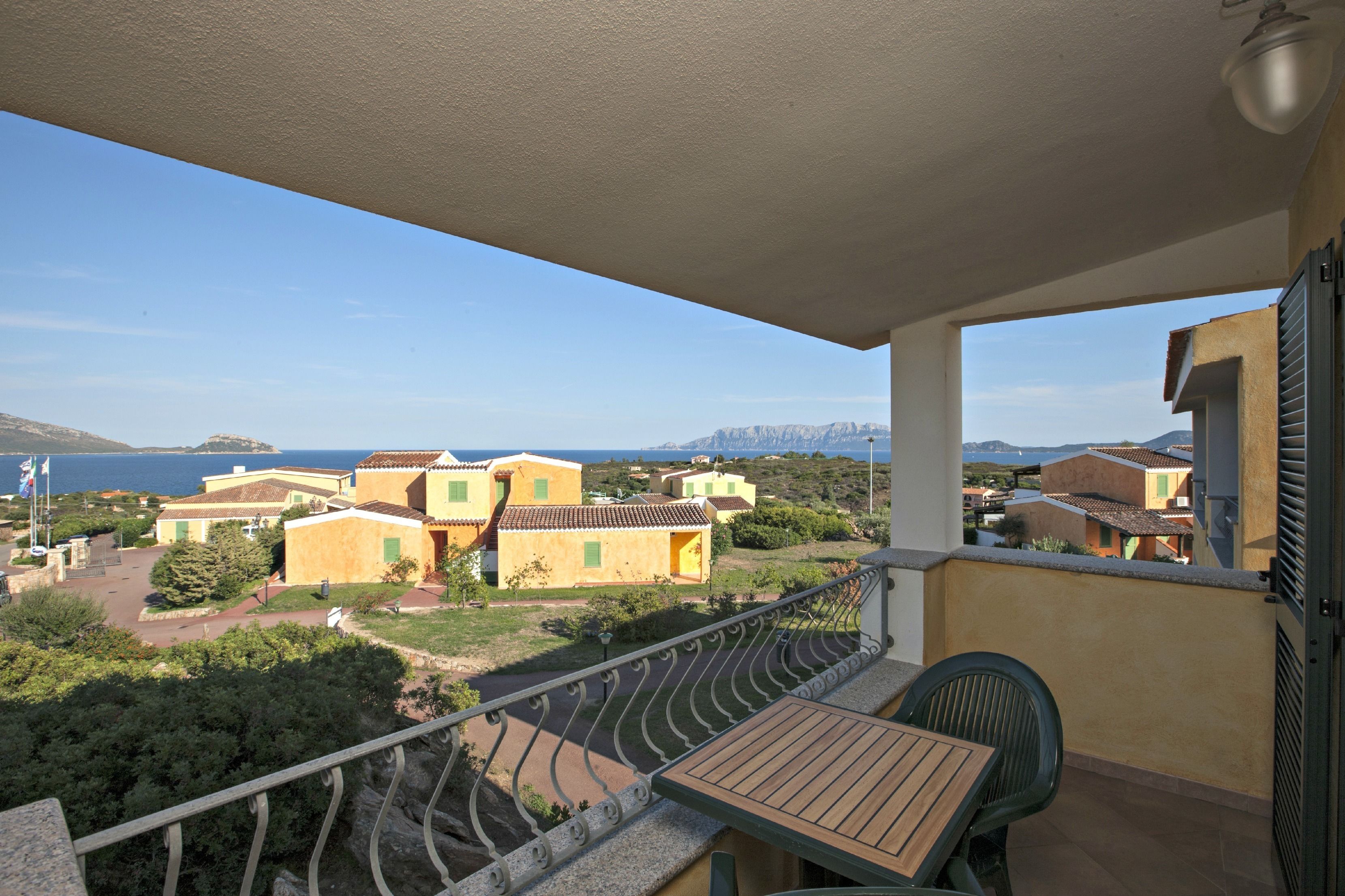 Un balcone con vista su un villaggio costiero, un tavolo e una sedia.