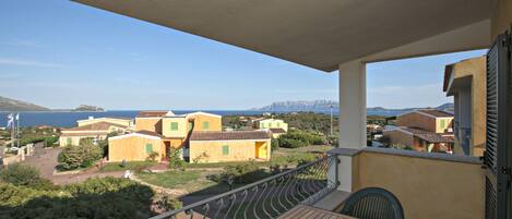 Un balcón con vistas a un pueblo costero, una mesa y una silla.