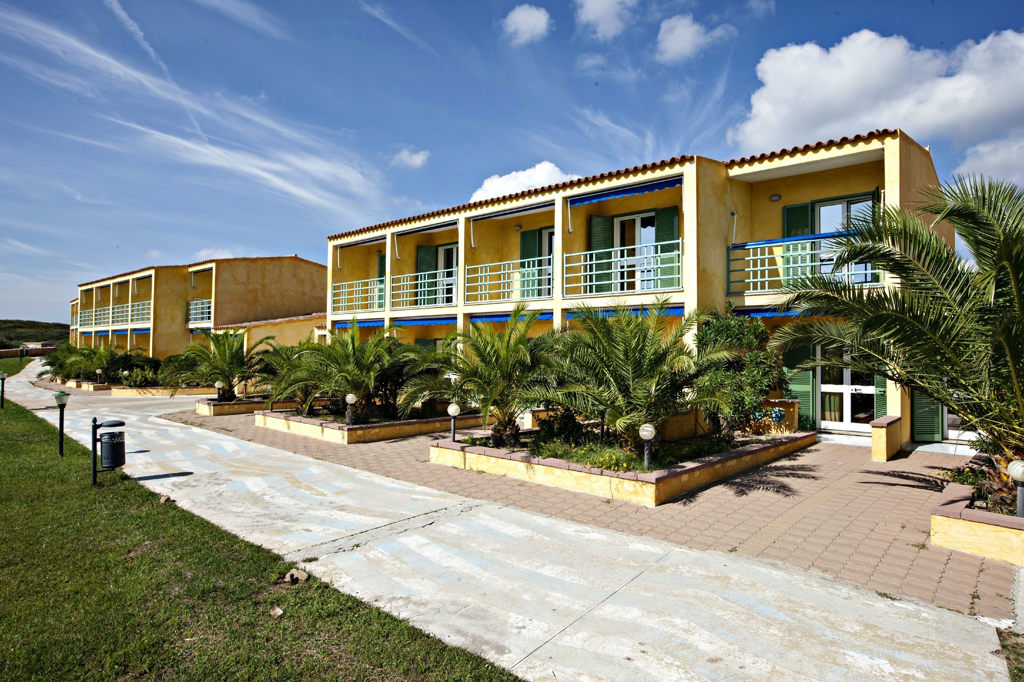 A hotel with a two-story structure, outdoor seating areas, and a paved walkway.
