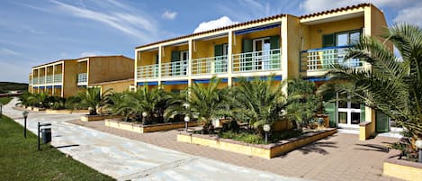 A hotel with a two-story structure, outdoor seating areas, and a paved walkway.