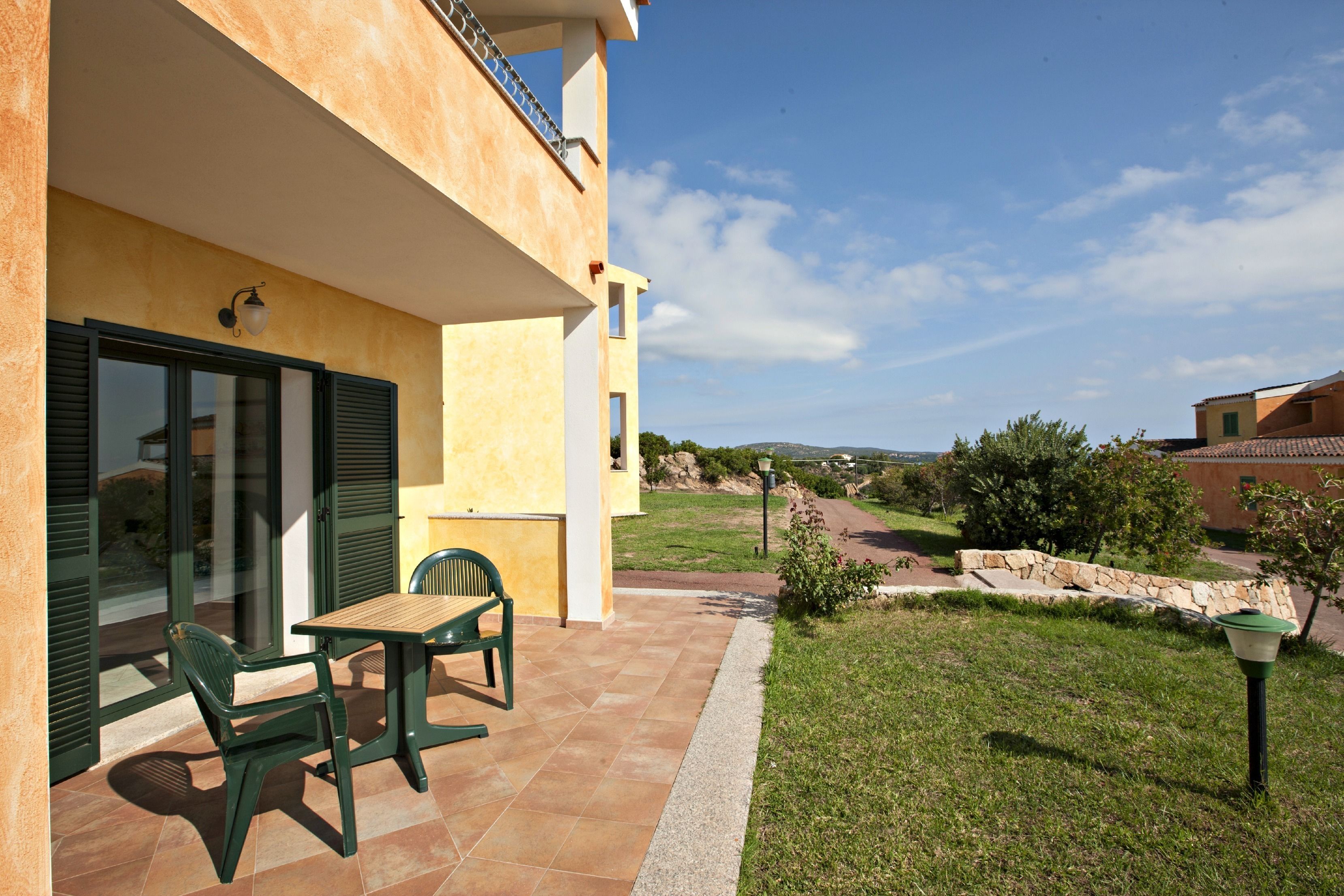 A patio with a table and chairs, a stone wall, and a view of the countryside.